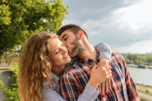 man kissing his partner at a park